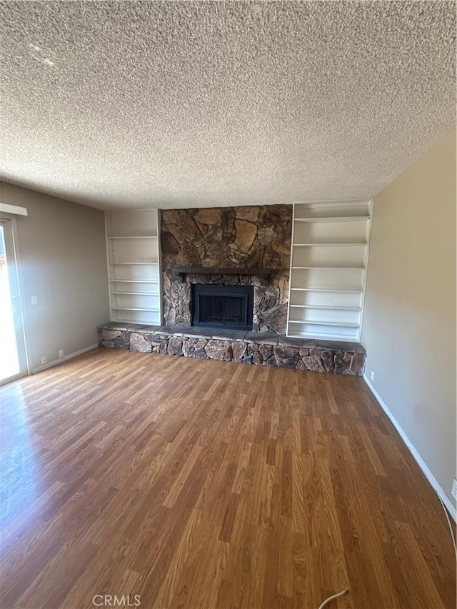 2854 Coronado Ave, San Diego, CA 92154 - unfurnished living room featuring a textured ceiling, built in shelves, wood finished floors, and a stone fireplace