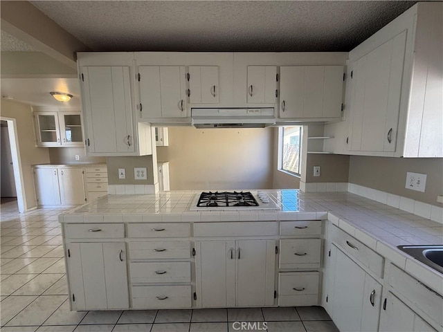 2854 Coronado Ave, San Diego, CA 92154 - kitchen featuring under cabinet range hood, white cabinets, gas stovetop, tile counters, and a textured ceiling