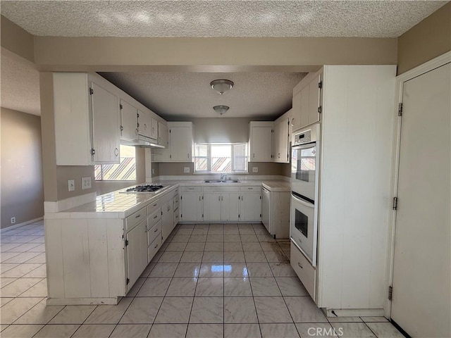 2854 Coronado Ave, San Diego, CA 92154 - kitchen featuring a textured ceiling, white cabinetry, white double oven, tile counters, and light tile patterned floors