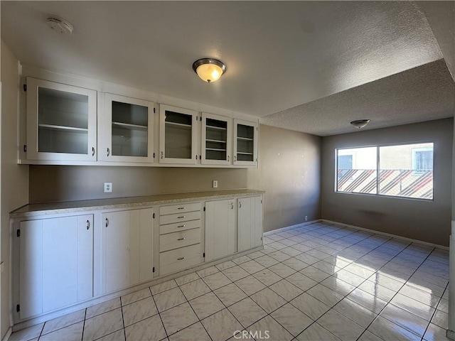 2854 Coronado Ave, San Diego, CA 92154 - kitchen featuring light countertops, white cabinetry, glass insert cabinets, and a textured ceiling