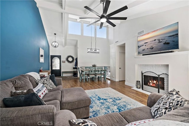 1828 Wintergreen, Escondido, CA 92026 - living area featuring ceiling fan, wood finished floors, beam ceiling, a towering ceiling, and a brick fireplace