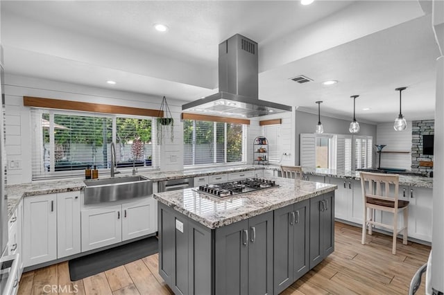 3652 San Joaquin Ave, Los Alamitos, CA 90720 - kitchen featuring tasteful backsplash, island range hood, a center island, light wood-type flooring, and white cabinetry