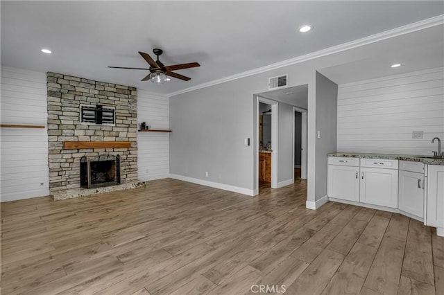3652 San Joaquin Ave, Los Alamitos, CA 90720 - unfurnished living room with ceiling fan, light wood finished floors, a fireplace, crown molding, and wooden walls