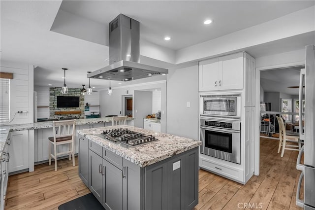 3652 San Joaquin Ave, Los Alamitos, CA 90720 - kitchen featuring island range hood, stainless steel appliances, light wood-type flooring, light stone countertops, and gray cabinetry