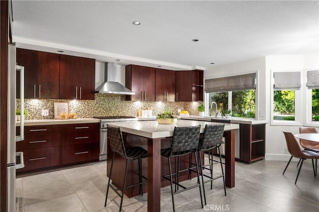 26356 Sorrell Pl, Laguna Hills, CA 92653 - kitchen featuring appliances with stainless steel finishes, wall chimney range hood, light countertops, a breakfast bar, and tasteful backsplash