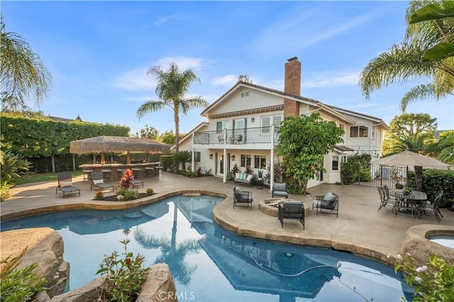 26356 Sorrell Pl, Laguna Hills, CA 92653 - rear view of house with a balcony, a patio area, a chimney, an outdoor pool, and an outdoor living space with a fire pit
