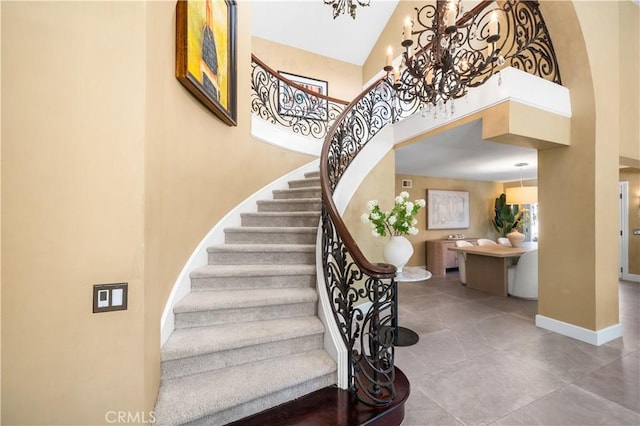 26356 Sorrell Pl, Laguna Hills, CA 92653 - staircase with a chandelier, a high ceiling, tile patterned flooring, and arched walkways