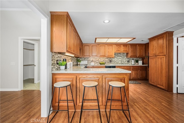 13311 Twin Hills Rd Unit 55H, Seal Beach, CA 90740 - kitchen with backsplash, a peninsula, light countertops, wood finished floors, and a breakfast bar