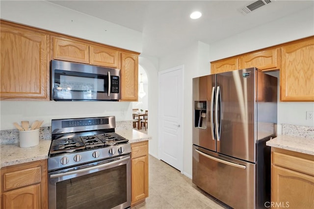 11246 Pleasant Hills Dr, Apple Valley, CA 92308 - kitchen with appliances with stainless steel finishes, arched walkways, light stone counters, light tile patterned floors, and recessed lighting