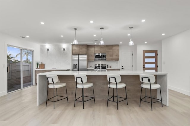 4143 Cole Way, San Diego, CA 92117 - kitchen featuring stainless steel appliances, recessed lighting, light countertops, a large island with sink, and light wood-style flooring