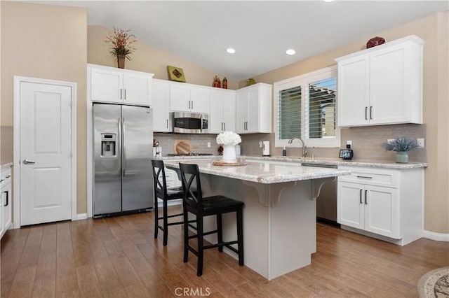 41798 Aviv Ct, Murrieta, CA 92562 - kitchen featuring stainless steel appliances, a breakfast bar area, white cabinetry, lofted ceiling, and recessed lighting