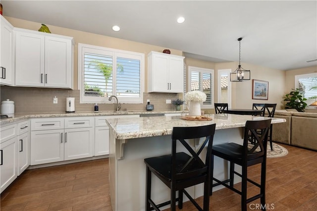 41798 Aviv Ct, Murrieta, CA 92562 - kitchen featuring white cabinets, a breakfast bar area, dark wood finished floors, and recessed lighting