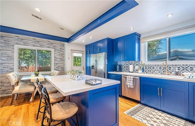 8638 Yorktown Ave, Los Angeles, CA 90045 - kitchen featuring appliances with stainless steel finishes, blue cabinetry, a kitchen breakfast bar, light wood-style floors, and recessed lighting