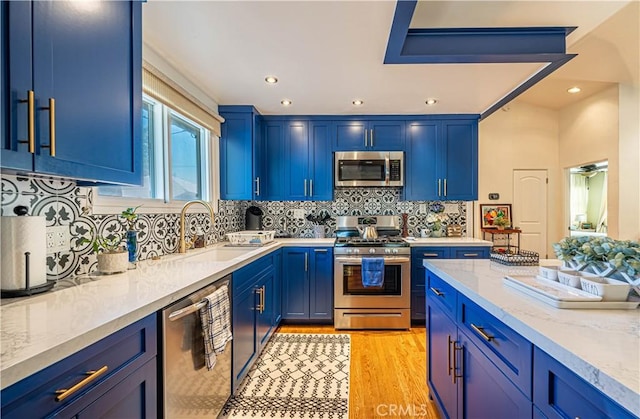 8638 Yorktown Ave, Los Angeles, CA 90045 - kitchen featuring appliances with stainless steel finishes, blue cabinets, backsplash, recessed lighting, and light wood finished floors