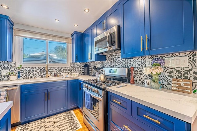 8638 Yorktown Ave, Los Angeles, CA 90045 - kitchen with stainless steel appliances, blue cabinets, tasteful backsplash, recessed lighting, and light wood finished floors