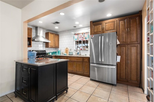 117 N Morada Ave, West Covina, CA 91790 - kitchen featuring freestanding refrigerator, wall chimney range hood, black gas range oven, tasteful backsplash, and brown cabinets