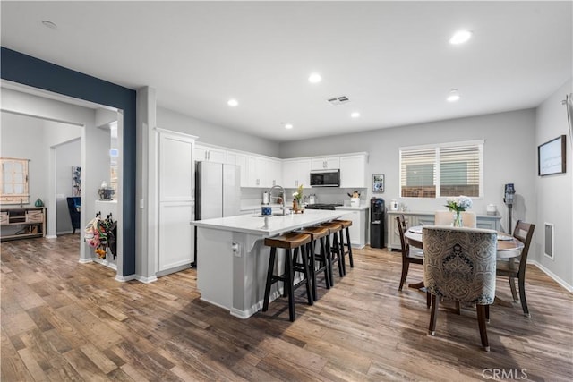 3558 Mt San Gorgonia Ave, Rosamond, CA 93560 - kitchen featuring stainless steel microwave, wood finished floors, light countertops, white cabinetry, and recessed lighting
