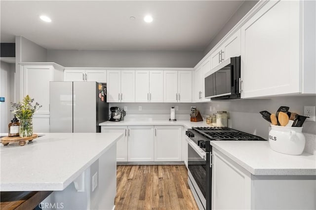 3558 Mt San Gorgonia Ave, Rosamond, CA 93560 - kitchen featuring appliances with stainless steel finishes, white cabinets, light wood-type flooring, and recessed lighting