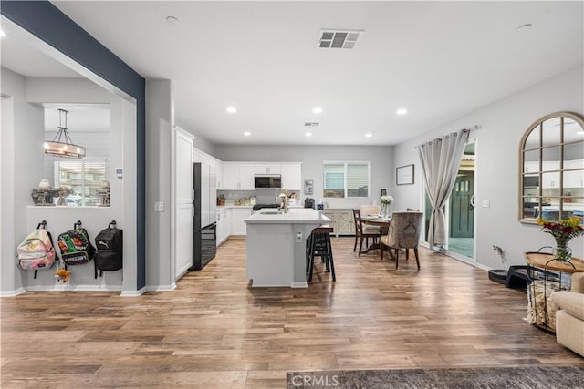 3558 Mt San Gorgonia Ave, Rosamond, CA 93560 - kitchen featuring stainless steel microwave, light wood-type flooring, a kitchen bar, light countertops, and recessed lighting