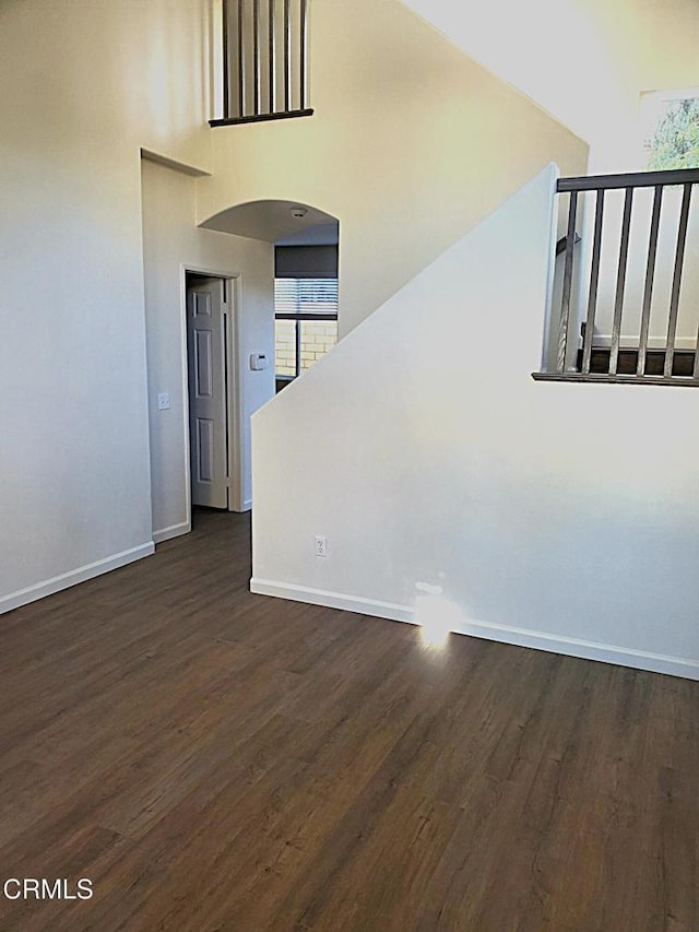 1123 Paseo Las Nubes, Oxnard, CA 93030 - unfurnished living room with dark wood finished floors, arched walkways, a towering ceiling, and healthy amount of natural light