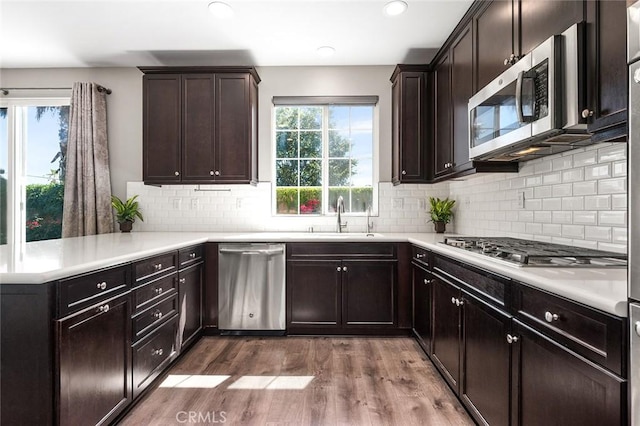 28419 Sunflower St, Highland, CA 92346 - kitchen featuring appliances with stainless steel finishes, wood finished floors, light countertops, backsplash, and dark brown cabinets
