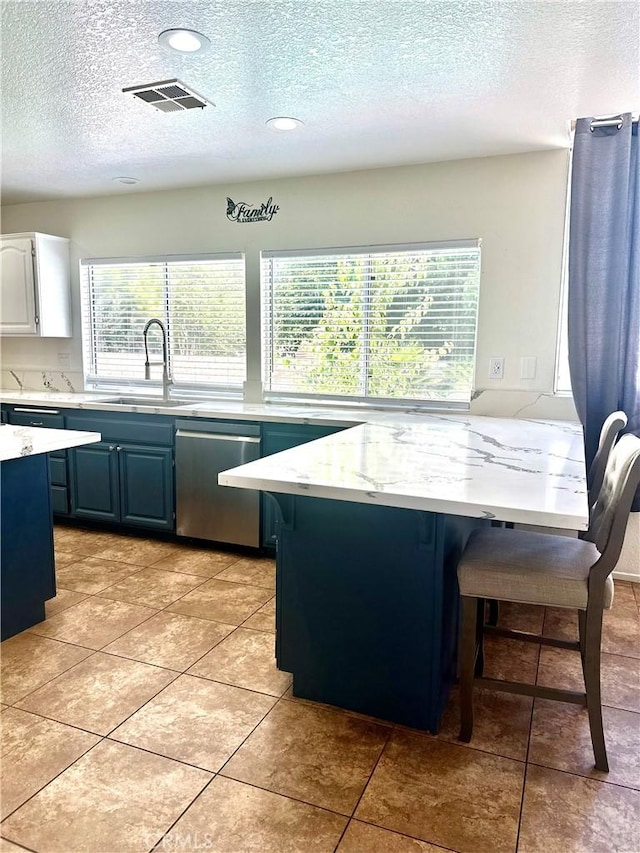 3415 Genoa Pl, Palmdale, CA 93551 - kitchen with stainless steel dishwasher, a textured ceiling, a kitchen breakfast bar, plenty of natural light, and blue cabinets