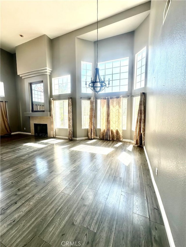 3415 Genoa Pl, Palmdale, CA 93551 - unfurnished living room featuring a towering ceiling, a chandelier, wood finished floors, and a fireplace