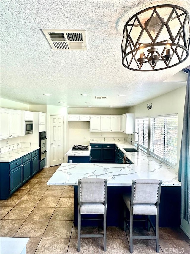 3415 Genoa Pl, Palmdale, CA 93551 - kitchen featuring a peninsula, blue cabinetry, white cabinetry, appliances with stainless steel finishes, and a textured ceiling
