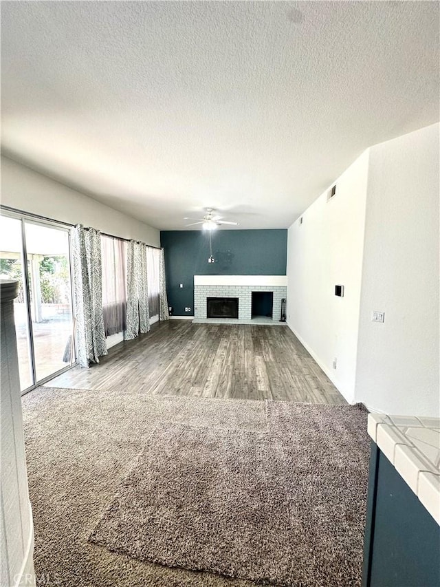 3415 Genoa Pl, Palmdale, CA 93551 - unfurnished living room with wood finished floors, a tiled fireplace, a ceiling fan, and a textured ceiling