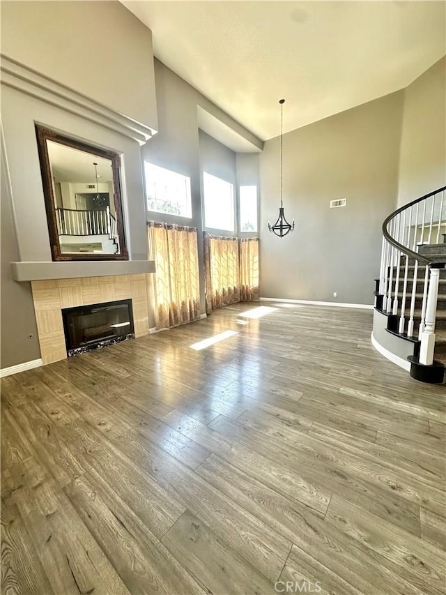 3415 Genoa Pl, Palmdale, CA 93551 - unfurnished living room with wood finished floors, a fireplace, stairway, and lofted ceiling