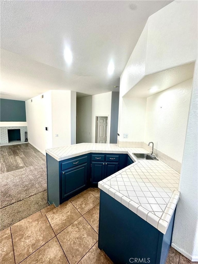 3415 Genoa Pl, Palmdale, CA 93551 - kitchen with a peninsula, open floor plan, blue cabinets, tile counters, and a textured ceiling