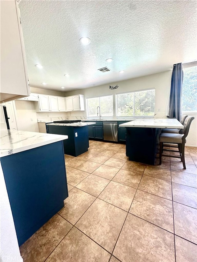 3415 Genoa Pl, Palmdale, CA 93551 - kitchen featuring stainless steel dishwasher, a kitchen island, a textured ceiling, white cabinetry, and light stone counters