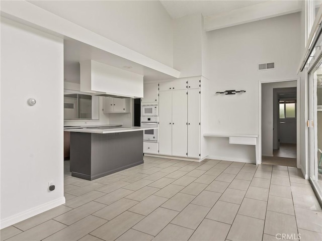 2640 Via Anacapa, Palos Verdes Estates, CA 90274 - kitchen with white appliances, a high ceiling, light countertops, white cabinetry, and a kitchen island