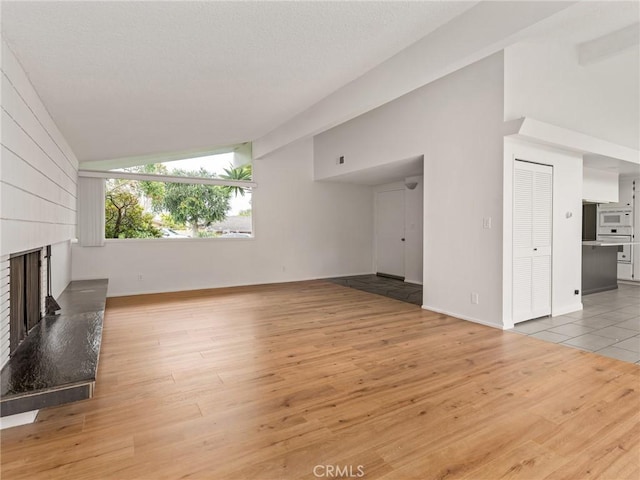 2640 Via Anacapa, Palos Verdes Estates, CA 90274 - unfurnished living room with vaulted ceiling, a large fireplace, and light wood-type flooring