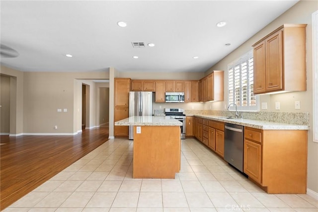 26135 Palm Breeze Ln, Menifee, CA 92586 - kitchen with stainless steel appliances, a center island, recessed lighting, light stone counters, and light tile patterned floors