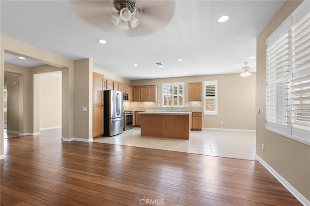26135 Palm Breeze Ln, Menifee, CA 92586 - kitchen with ceiling fan, appliances with stainless steel finishes, light countertops, open floor plan, and a kitchen island