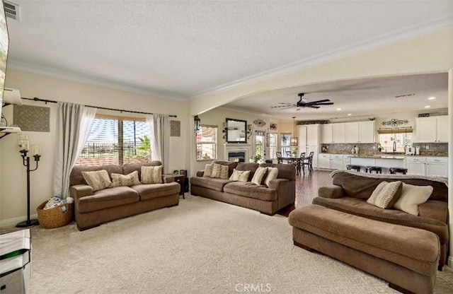 4011 Prestwick Ln, Palmdale, CA 93551 - living room with crown molding, a ceiling fan, a textured ceiling, a lit fireplace, and arched walkways