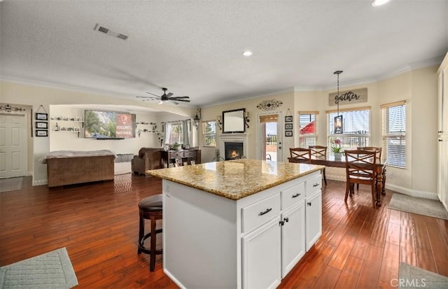 4011 Prestwick Ln, Palmdale, CA 93551 - kitchen with a warm lit fireplace, crown molding, open floor plan, a center island, and white cabinetry