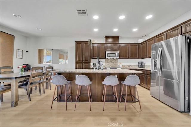 3026 Neary Ct, Rosamond, CA 93560 - kitchen featuring appliances with stainless steel finishes, light wood-style floors, a breakfast bar area, dark brown cabinets, and recessed lighting