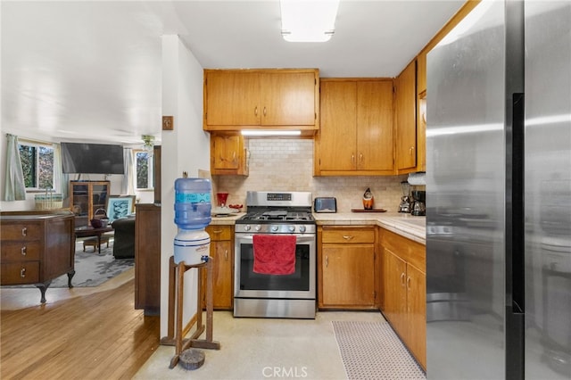 29239 Lake Brook Ave, Cedar Glen, CA 92321 - kitchen with stainless steel appliances, tasteful backsplash, a glass covered fireplace, brown cabinetry, and tile counters