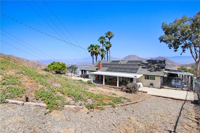 8555 Pigeon Pass Rd, Moreno Valley, CA 92557 - rear view of house with a patio, solar panels, a shingled roof, and a mountain view
