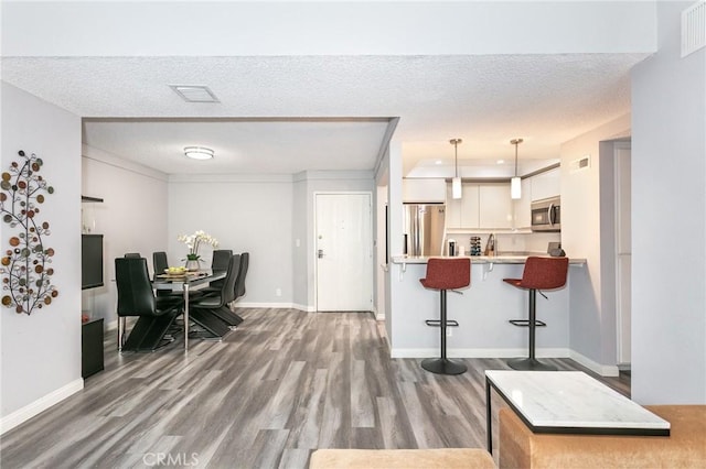 7800 Topanga Canyon Blvd Unit 324, Canoga Park, CA 91304 - kitchen with stainless steel appliances, a kitchen breakfast bar, wood finished floors, light countertops, and white cabinets