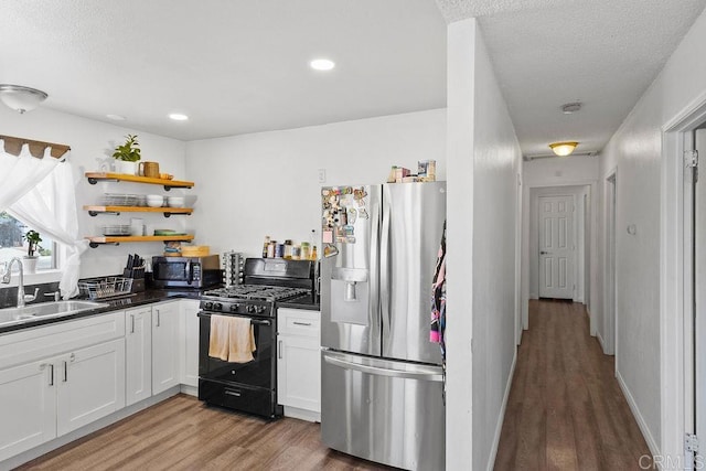 7023 Lisbon St, San Diego, CA 92114 - kitchen with stainless steel appliances, open shelves, light wood-style floors, dark countertops, and white cabinetry