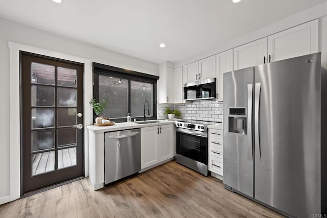 2282 Caminito Pescado Unit 44, San Diego, CA 92107 - kitchen featuring stainless steel appliances, white cabinetry, light countertops, decorative backsplash, and wood finished floors