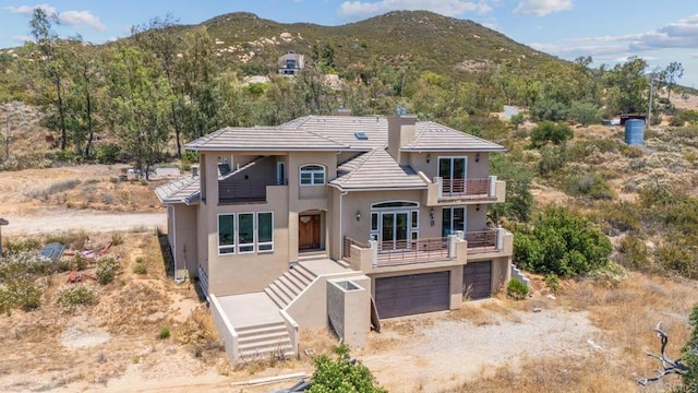 20202 Deerhorn Valley Rd, Jamul, CA 91935 - view of front facade featuring a balcony, stucco siding, a mountain view, dirt driveway, and a garage