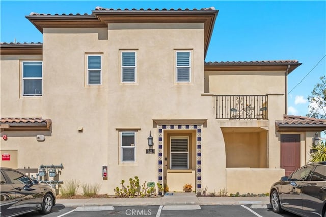 17557 Newland St Unit 101, Huntington Beach, CA 92647 - view of front of house with a balcony, stucco siding, uncovered parking, and a tiled roof