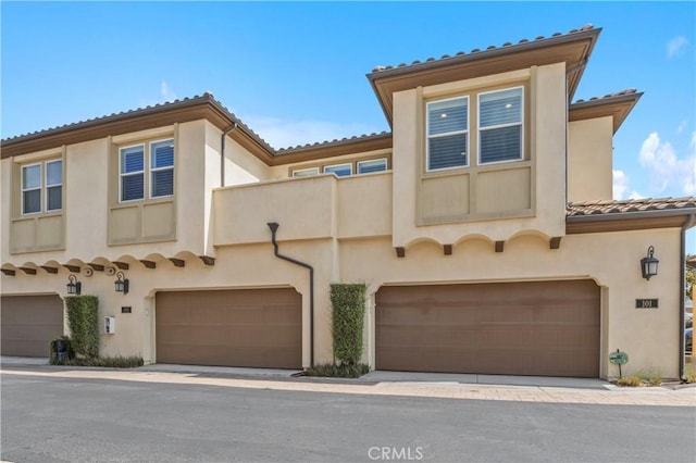 17557 Newland St Unit 101, Huntington Beach, CA 92647 - mediterranean / spanish house with stucco siding, a tiled roof, and an attached garage