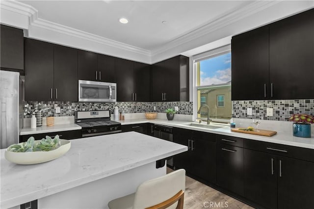 17557 Newland St Unit 101, Huntington Beach, CA 92647 - kitchen featuring stainless steel appliances, dark cabinets, crown molding, a kitchen bar, and backsplash