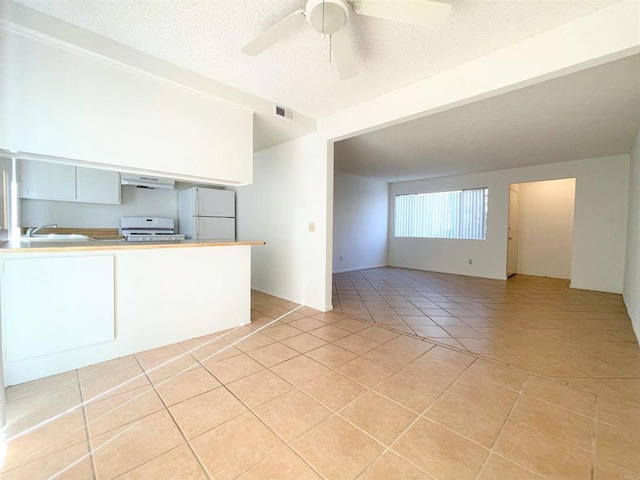 1249 Arcadia Ave, Vista, CA 92084 - kitchen featuring freestanding refrigerator, exhaust hood, light tile patterned floors, stove, and white cabinetry