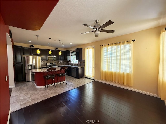 24112 Joshua Dr, Valencia, CA 91354 - kitchen with stainless steel appliances, a kitchen bar, a kitchen island, a ceiling fan, and tasteful backsplash